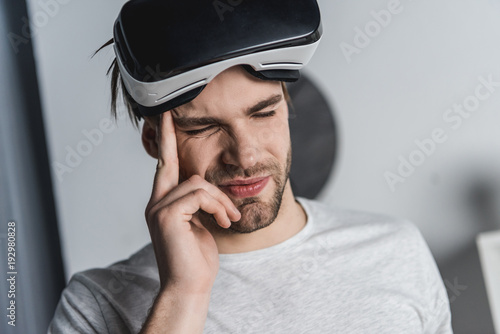 young man in virtual reality headset having headache