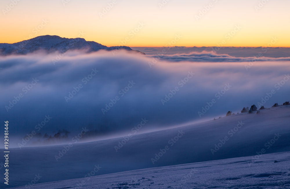 Clouds over the snow covered mountain range of the Vercors, France, during a winter dusk.