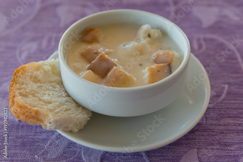 soup puree in a white bowl with croutons on a napkin and background fabric photo