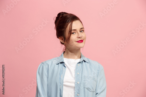 The happy business woman standing and smiling against pink background.