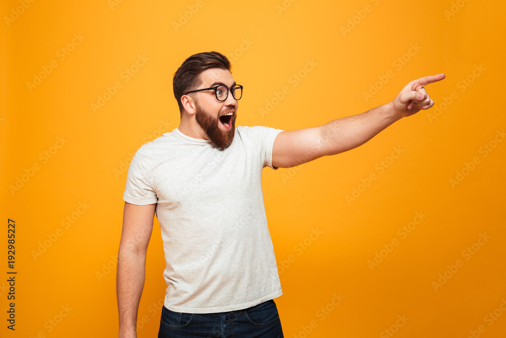 Portrait of an excited bearded man in eyeglasses pointing Portrait of an excited bearded man in eyeglasses pointing