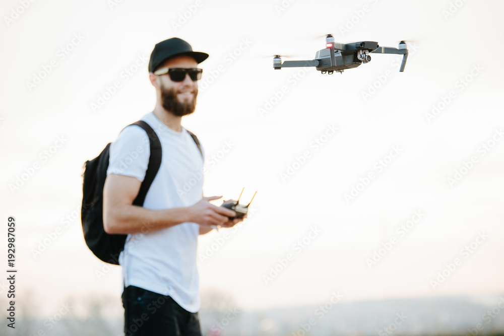 Man flying a drone in the city using a controller - obrazy, fototapety, plakaty 