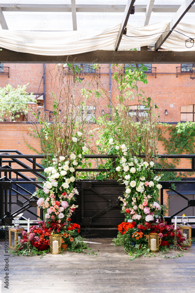 Obraz premium Wedding arch with a lot of fresh flowers and candles on floor. Flower decoration.