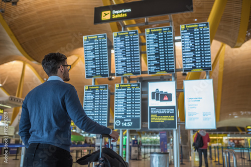 Photography man checking his flight on the timetable display at the airport
