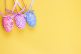 Easter holiday background. Pastel coloured decorated easter eggs on a bright yellow background