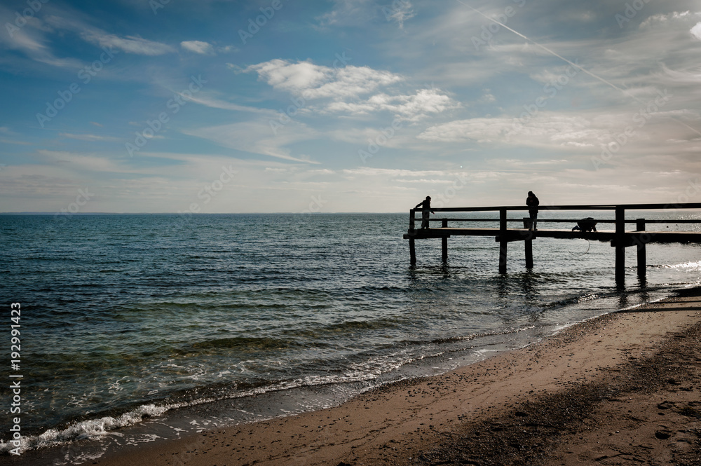 Children play on jetty on the beach in autumn