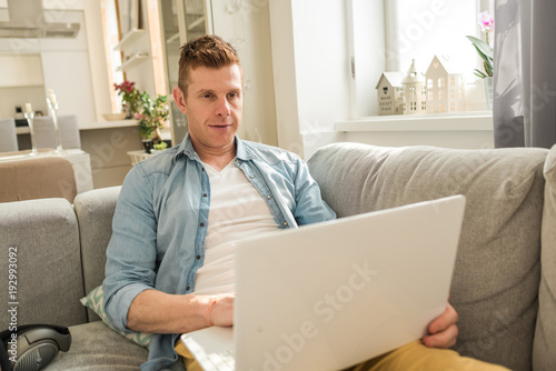 young Man sitting in sofa and using laptop © Erika