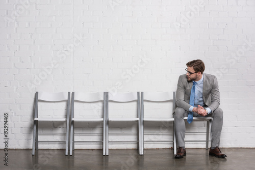 caucasian businessman looking at empty chairs while waiting for job interview