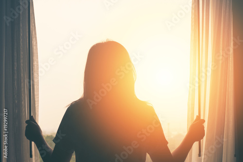 young woman stand in the bedroom open curtain see sunrise after wake up