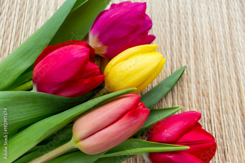 bouquet of colored tulips on a bamboo surface