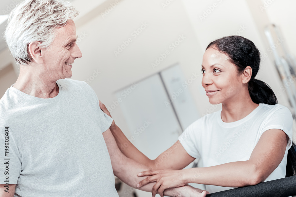 Fototapeta premium Nice atmosphere. Inspired energetic old grey-haired man smiling and a cheerful dark-haired dark-eyed woman sitting near him and they looking at each other