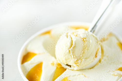 Vanilla ice cream scoop background. Summer food concept, copy space, top view. Scooped texture. Scooping out yellow mango ice-cream.