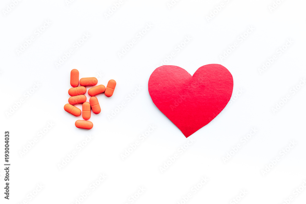Fototapeta premium Vitamins of drugs for heart. Color pills near heart sign on white background top view copy space