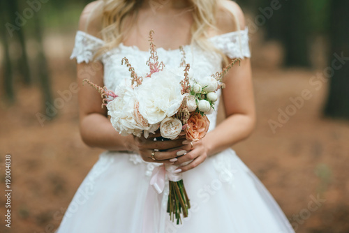 Fototapeta Naklejka Na Ścianę i Meble -  bride in nature with a beautiful wedding bouquet
