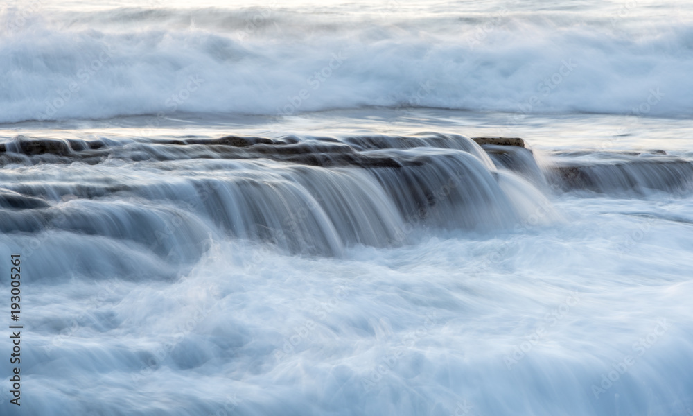 Rocky seashore with wavy ocean and waves crashing on the rocks Rocky seashore with wavy ocean and waves crashing on the rocks