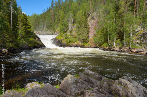 View from the river bank on waterfall in northern Finland in summer.