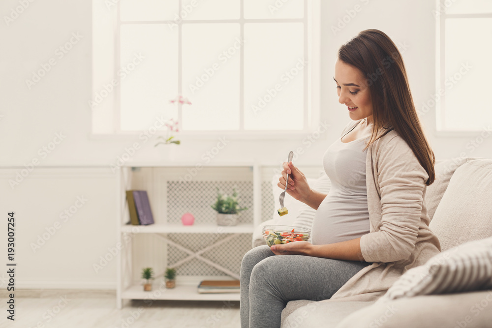 Young pregnant woman eating fresh green salad