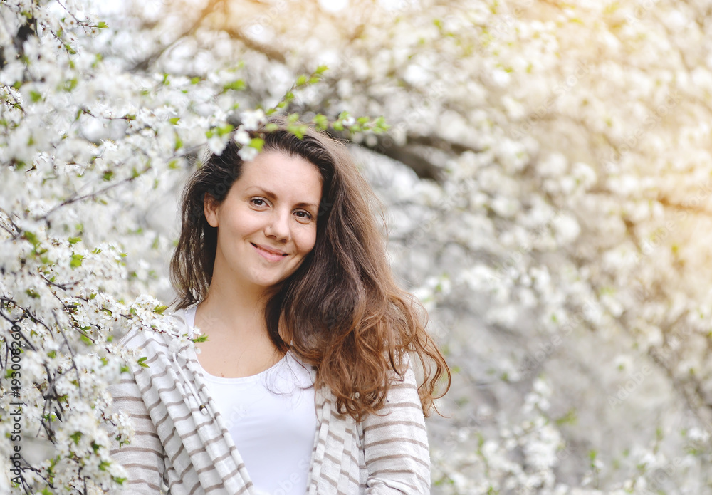 young woman stands near a blossoming tree in a spring park. young woman stands near a blossoming tree in a spring park.