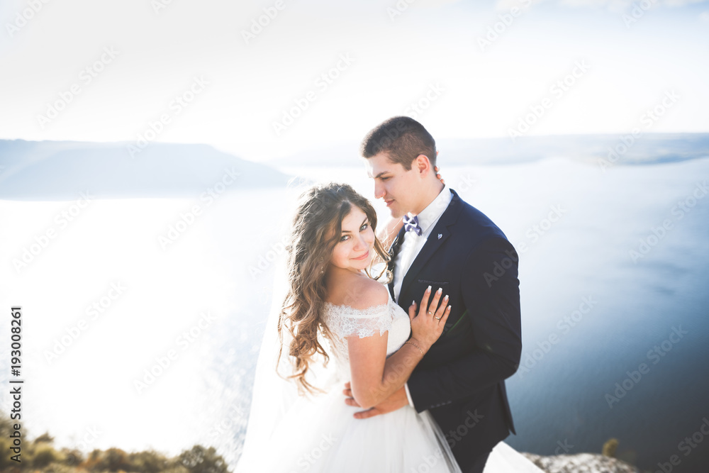 Wedding couple kissing and hugging on rocks near blue sea Wedding couple kissing and hugging on rocks near blue sea