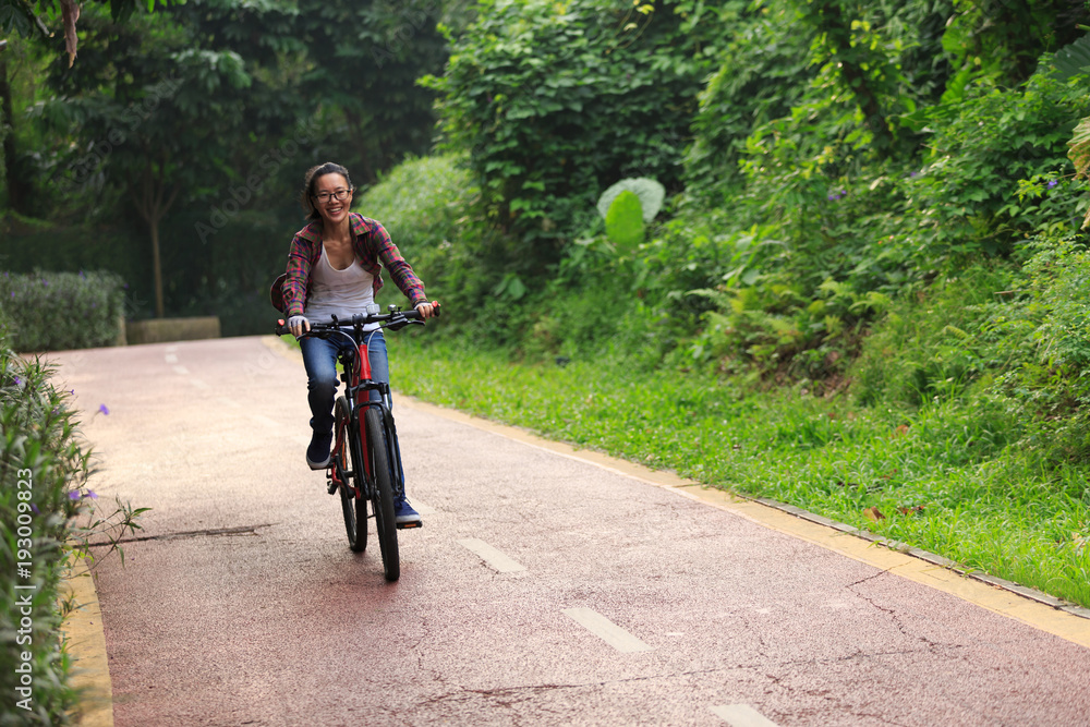 happy young woman cyclist cycling on forest trail