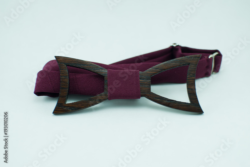 Stylish wooden bow tie with red soft cloth ribbon. Isolated