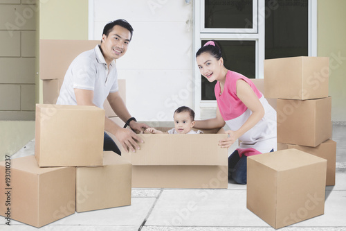 Young Asian family unpacking boxes in their new home