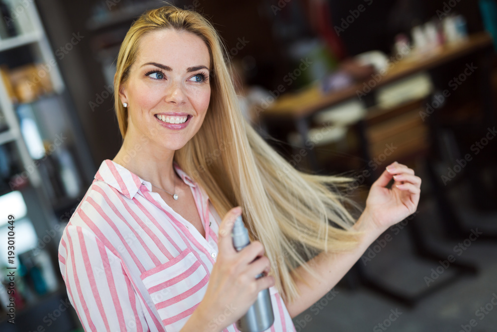 Woman spraying hairspray on beautiful long hair