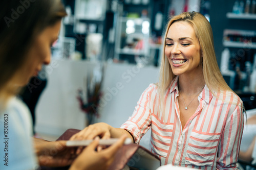Gorgeous young woman getting her nails done by a manicurist