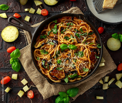 Vegetarian Italian Pasta Spaghetti alla Norma with eggplant, tomatoes, basil and parmesan cheese in rustic skillet pan.