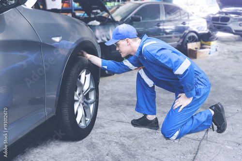 Caucasian mechanic checking on a tyre in a workshop