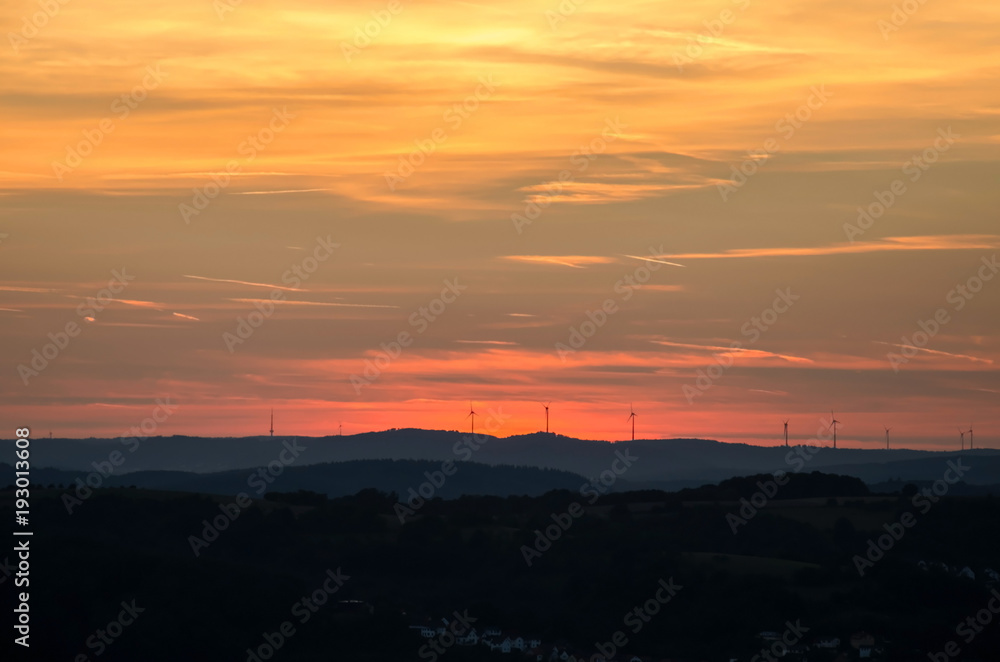 Sunset over Gladenbacher windpark. Silhouettes of wind generators on sunset background.