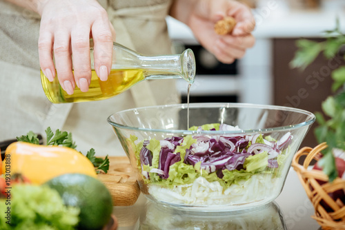 Pouring olive oil on freshly made salad. 