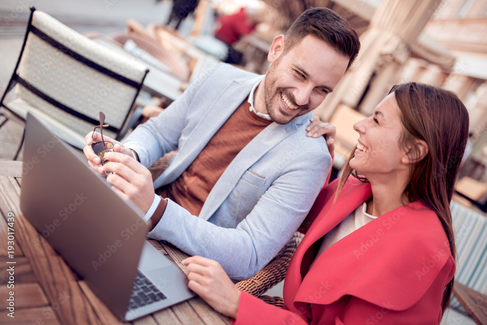 Smiling couple with laptop in cafe.