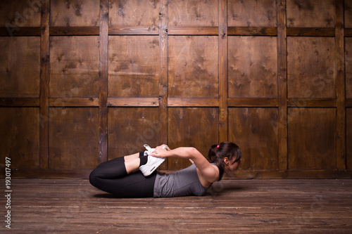 Young brunette doing exercise on floor. Isolated on wooden background.