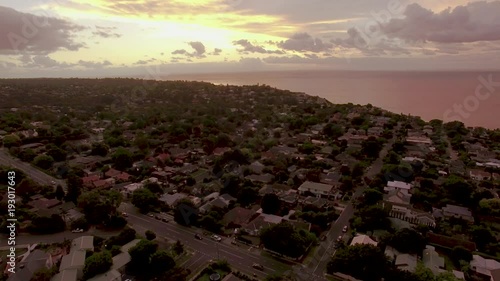 Aerial descend over typical Australian suburbian area near the coastline at sunset