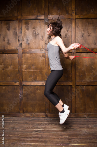 Girl jumping on rope. Isolted on wooden background.