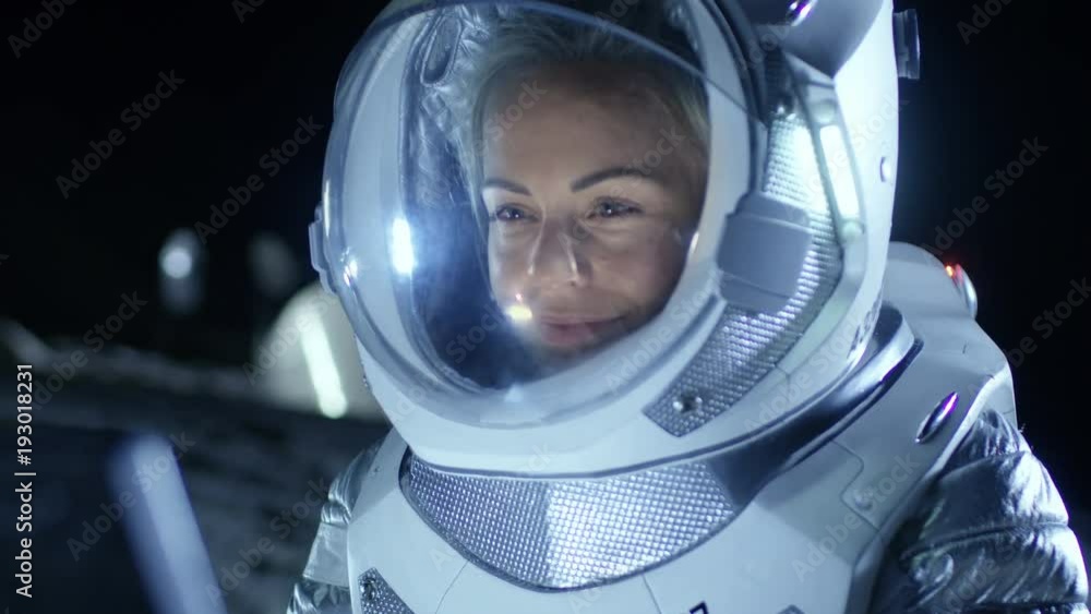 Female Astronaut Wearing Space Suit Works on a Laptop, Exploring Newly Discovered Planet, Communicating with the Earth. In the Background Living Station. Shot on RED EPIC-W 8K Helium Cinema Camera. Female Astronaut Wearing Space Suit Works on a Laptop, Exploring Newly Discovered Planet, Communicating with the Earth. In the Background Living Station. Shot on RED EPIC-W 8K Helium Cinema Camera.