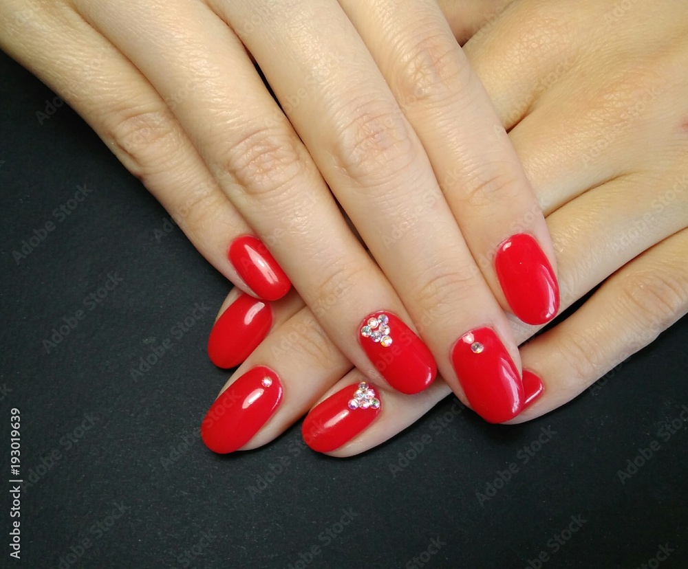 Elegant manicure. Red gel nail polish with rhinestones on a black  background. Stock Photo | Adobe Stock