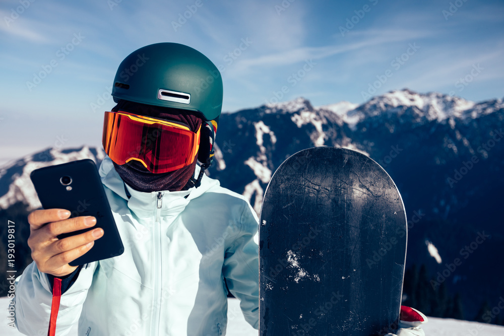 one snowboarder use smatphone on winter mountain top