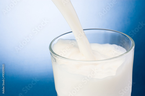 Pouring milk into glass on a blue background