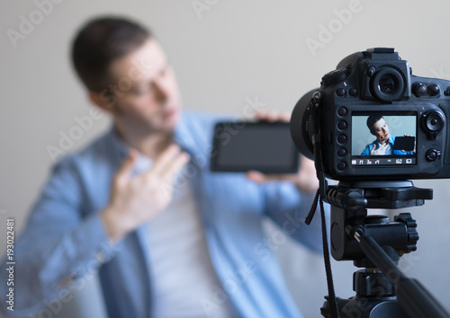 Man making video blog about tablet pc. Focus on camera. © M-Production