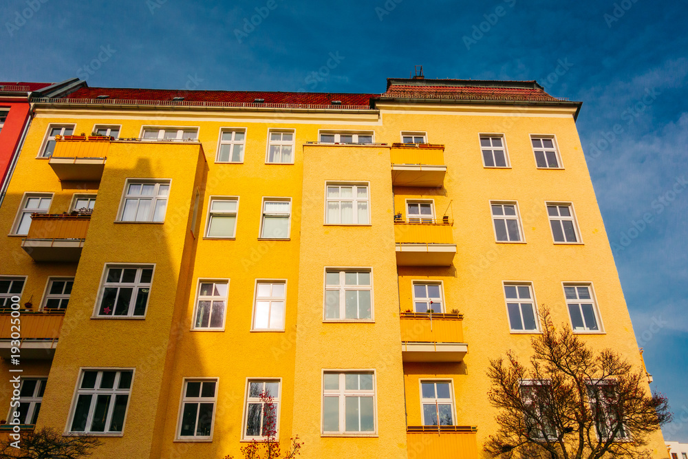 Fototapeta premium yellow colored apartment house with darken sky