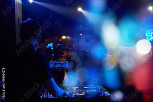 DJ plays at a party with a remote with vinyl records.