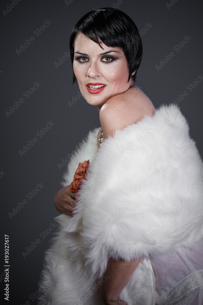 Brunette girl with short hair, French mane in the style of the 20s. She wears white fur coat and jewelry Brunette girl with short hair, French mane in the style of the 20s. She wears white fur coat and jewelry