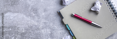 Panoramic view of gray desk top with notebook and crumpled sheets of paper