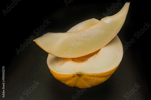 The cut yellow sweet melon on a black background