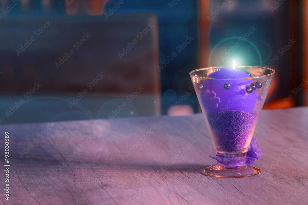 Piękny kielich z fioletową palącą się świecą na stole w restauracji. - obrazy, fototapety, plakaty 