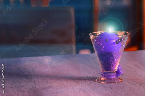 Piękny kielich z fioletową palącą się świecą na stole w restauracji.