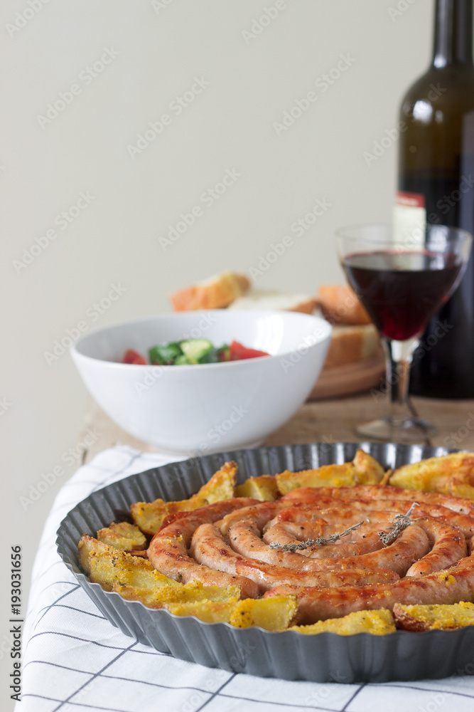 Aromatic meat sausages with potatoes, salad and wine on a wooden background. Selective focus.
