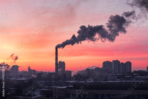 Smoke from a pipe factory against the background of the rising sun. Environmental problem of pollution of environment and air in large cities